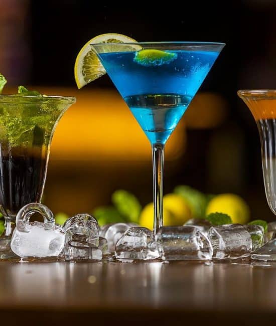 three cocktail glasses on wooden table