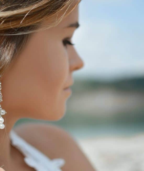 shallow focus photography of woman wearing dangling earrings holding her hair near mountain