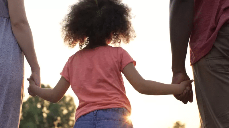 A kid holding her parents hands