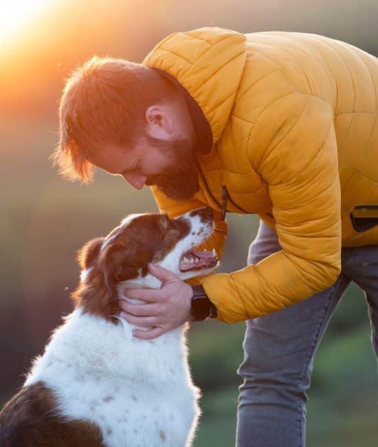 Man leaning and petting his dog.