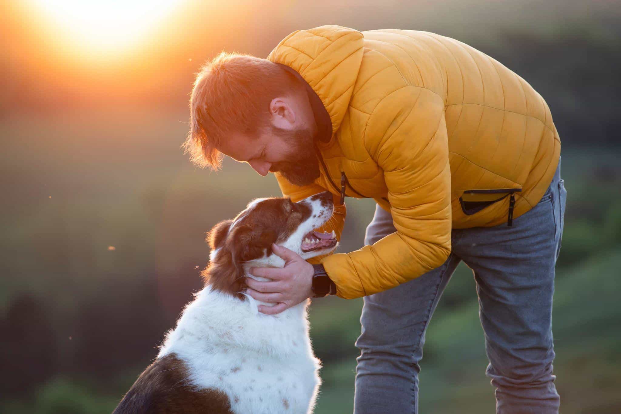 Man leaning and petting his dog.