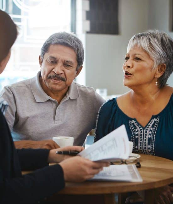 Two older people discussing a will with a lawyer and wondering, “How do you know if someone has a will?