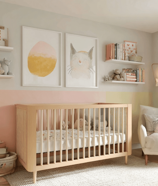A bright, modern nursery featuring a light wood crib centered against a wall painted in horizontal pastel stripes of pink, yellow, and light green, decorated.