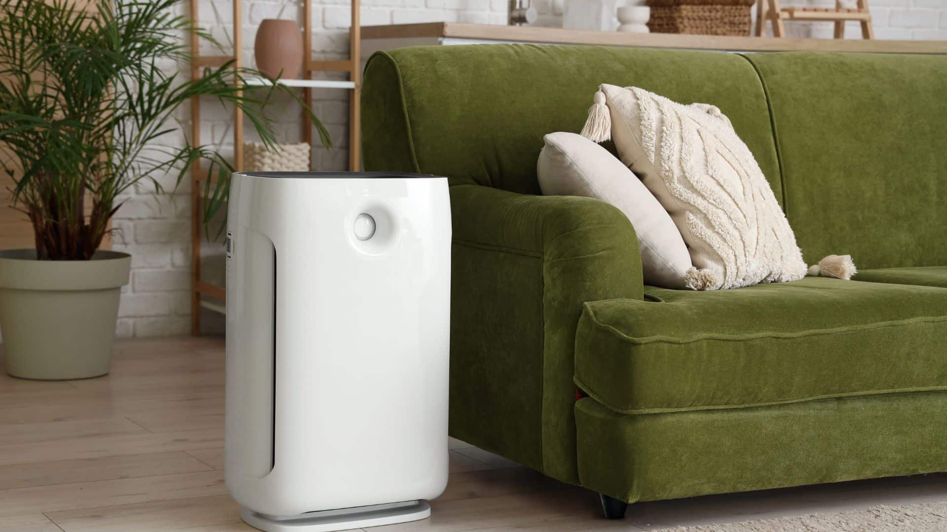 Air purifier placed beside a sofa in a living room, showing how air purifiers help with dust and improve indoor air quality at home