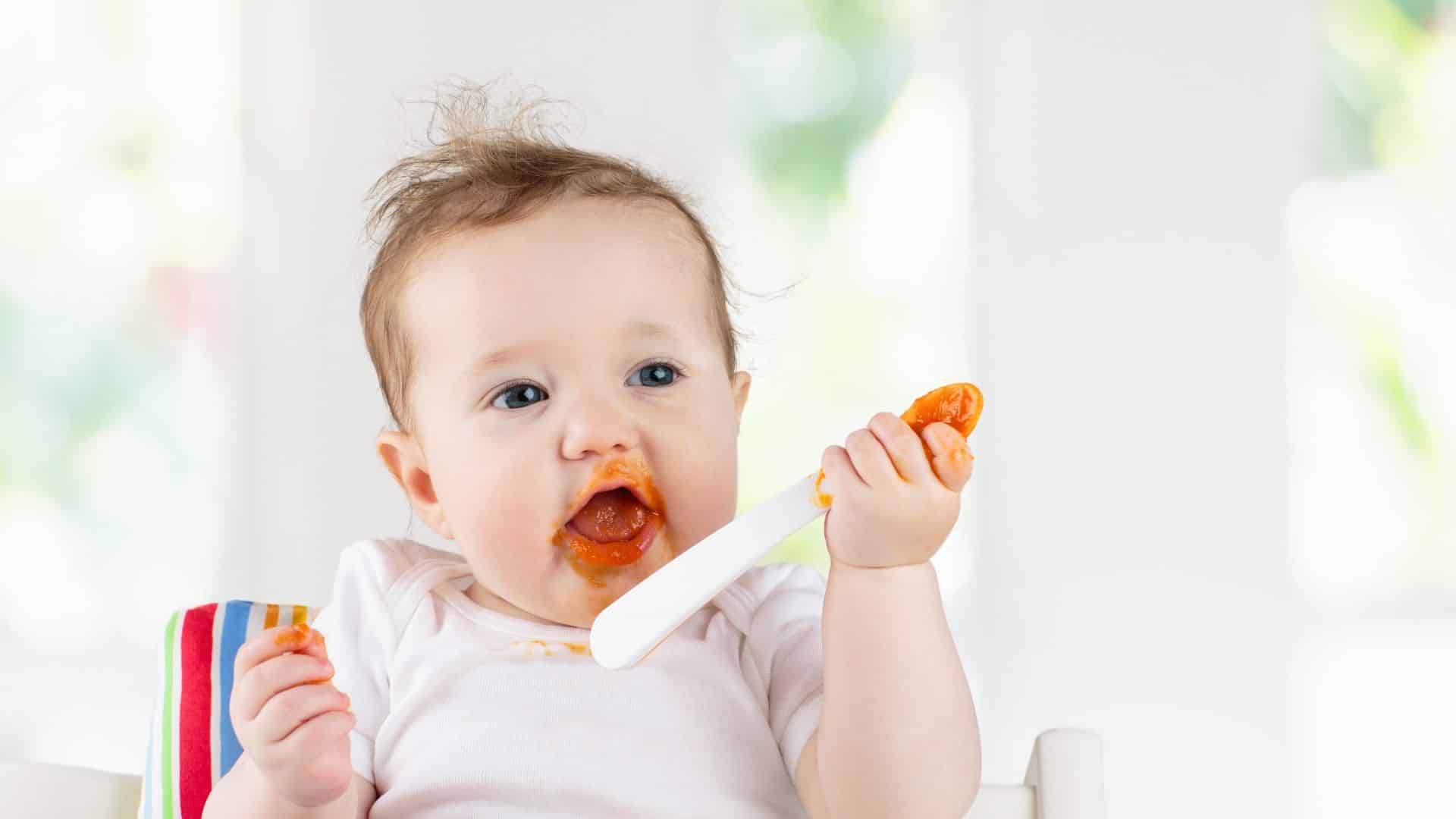 Baby eating mashed puree with spoon, showing homemade feeding moment related to how to make baby food for healthy infant nutrition