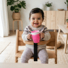Baby sitting in a high chair holding a sippy cup during mealtime