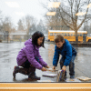 Child helping a friend pick up books that dropped on the floor