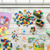 Colorful collage of indoor kids activities including crafts, puzzles, games, and toys arranged on a floor at home