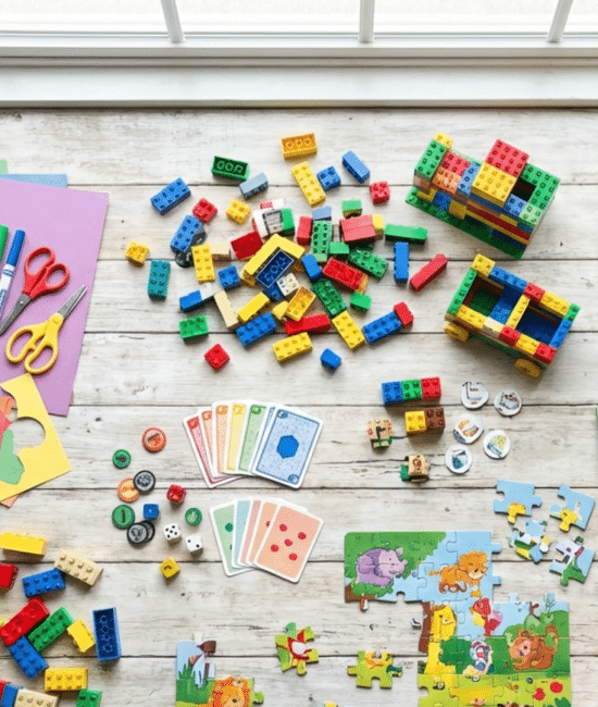 Colorful collage of indoor kids activities including crafts, puzzles, games, and toys arranged on a floor at home
