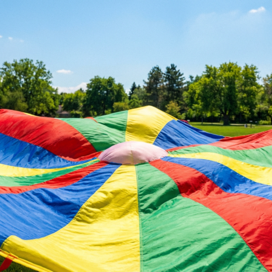 Colorful playground parachute spread on grass used for fun parachute games for kids
