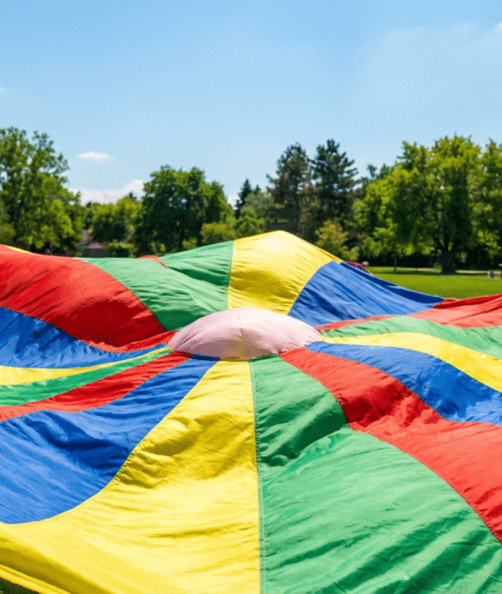 Colorful playground parachute spread on grass used for fun parachute games for kids
