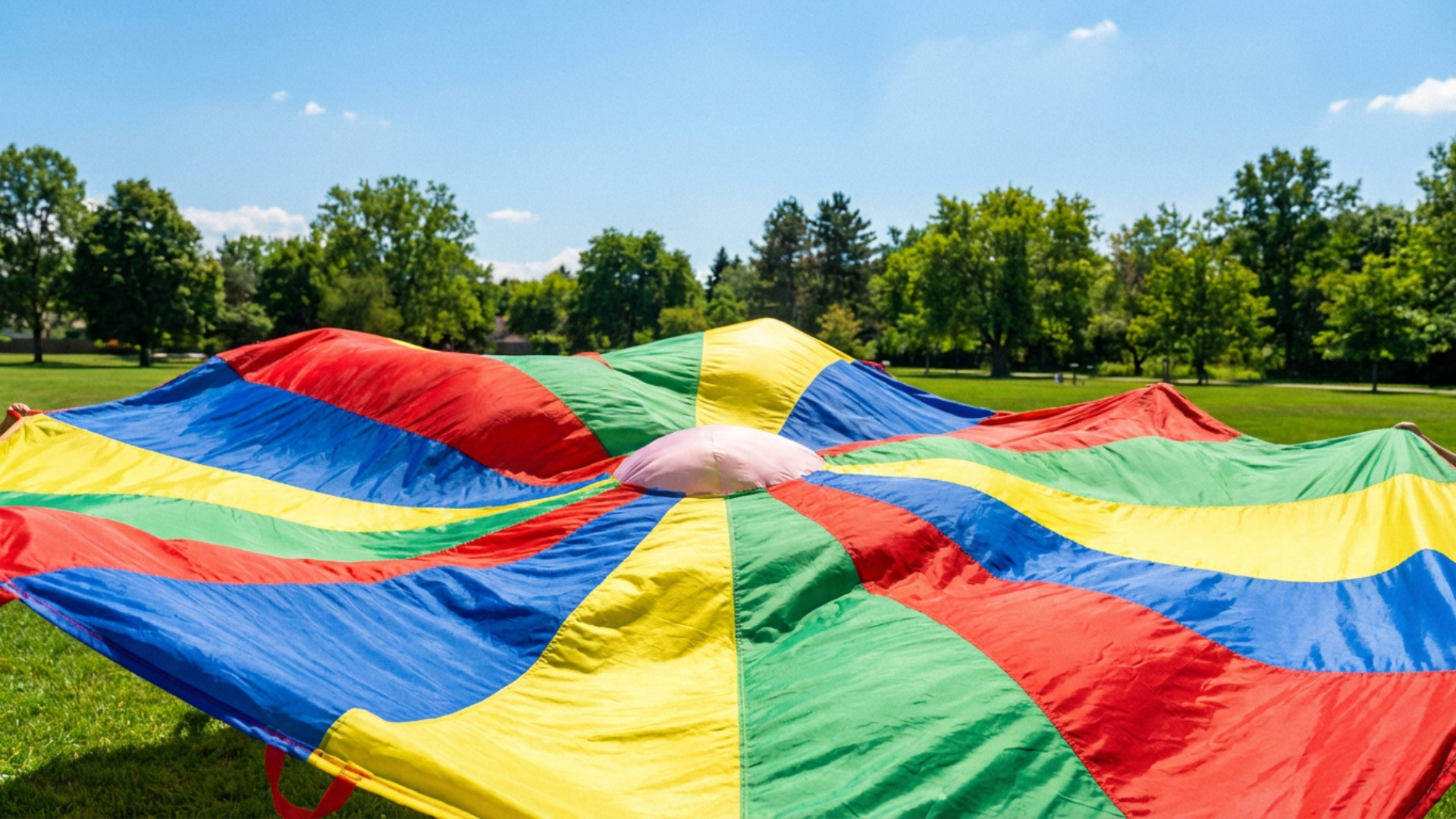 Colorful playground parachute spread on grass used for fun parachute games for kids