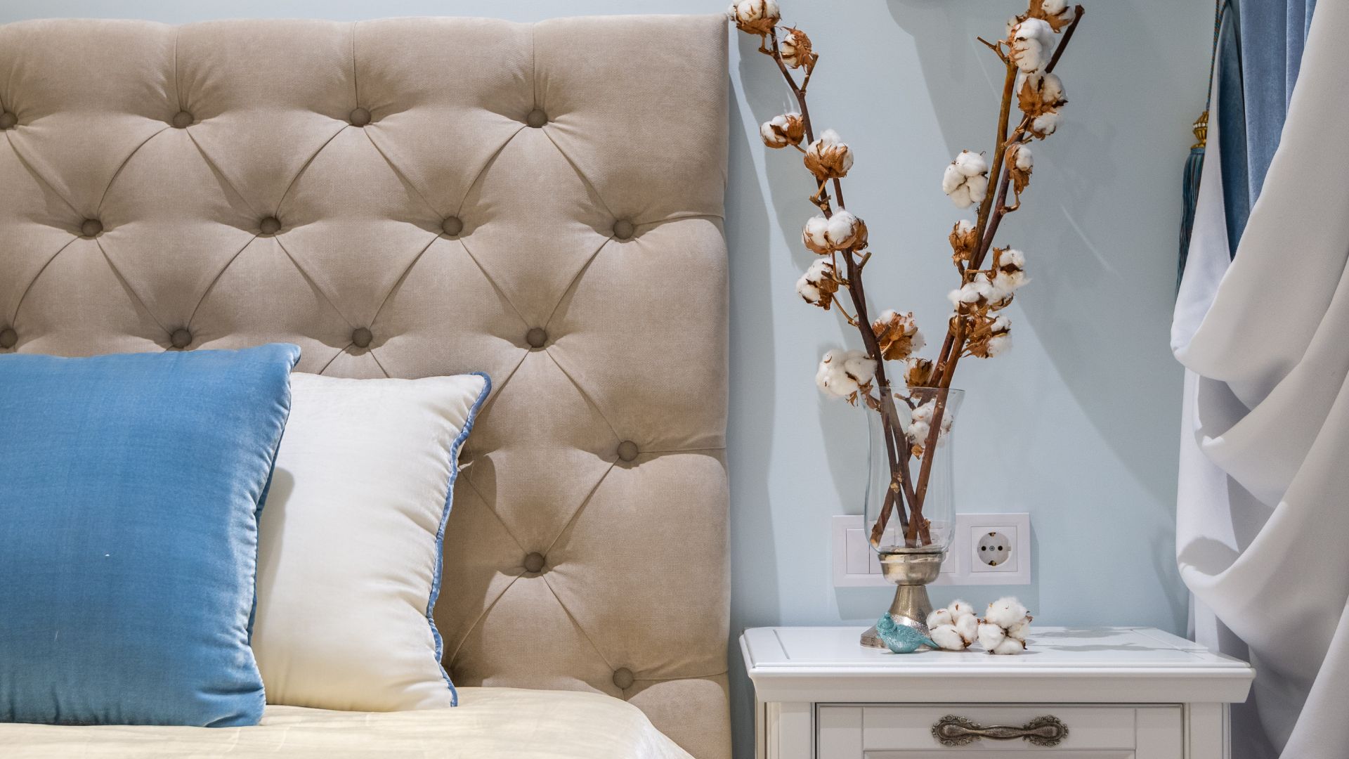 DIY upholstered headboard in beige tufted fabric with button detailing, paired with soft pillows and a styled bedside table in a cozy bedroom