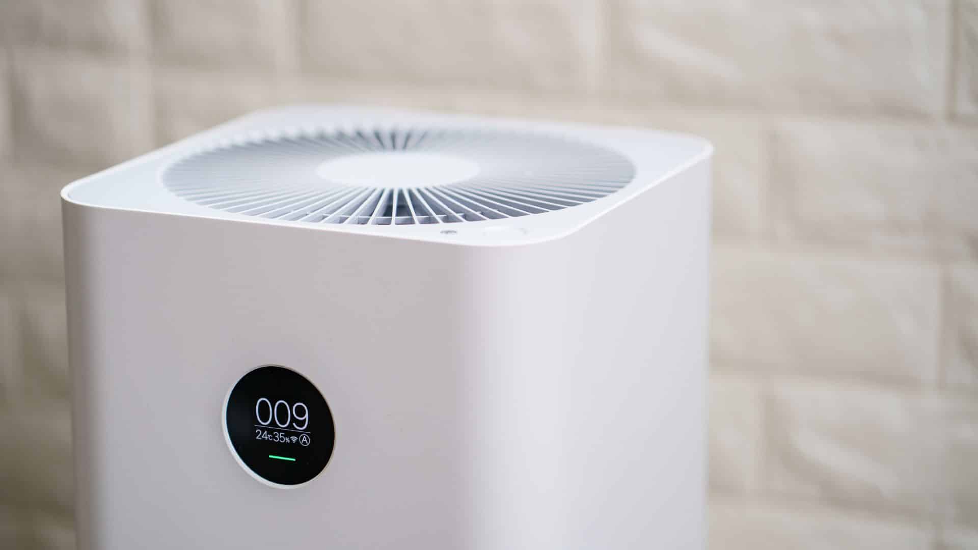 Modern air purifier with digital display running indoors, showing how air purifiers help with dust by filtering fine particles from the air