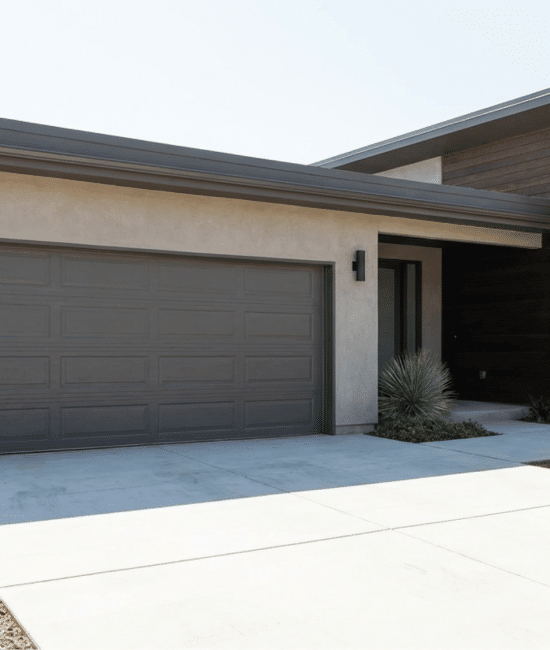 Modern single-story home featuring a stucco facade, dark wood siding, a gray garage door, and xeriscaping in the front yard.
