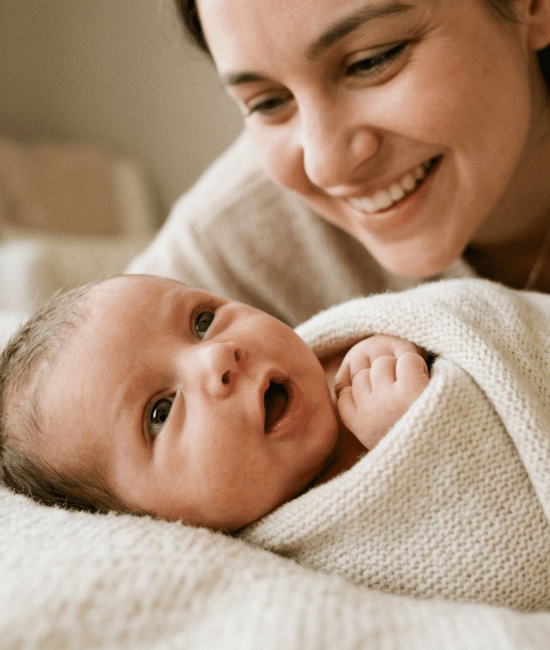Newborn baby making soft cooing sound while looking at smiling parent