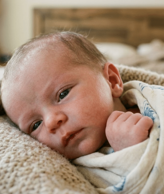 Newborn baby with soft blue-gray eyes under natural light showing early eye color variation