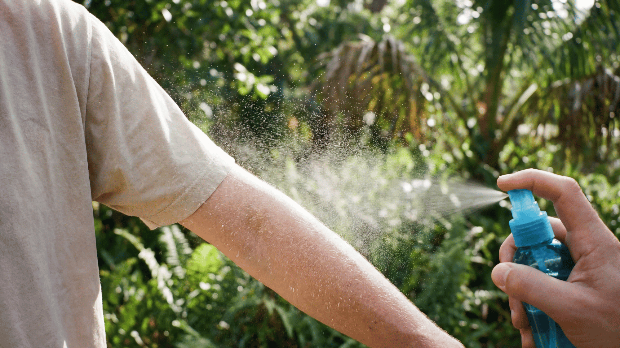 Person applying homemade mosquito repellent spray safely on forearm in a clean setting.
