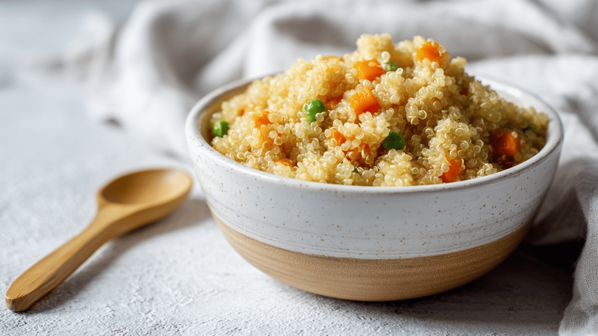 Quinoa and veggie mash in a baby bowl with spoon on a clean surface