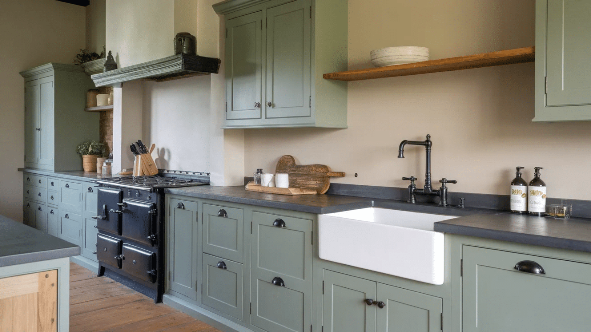 Sage green cabinets with black accents adding contrast in a rustic modern kitchen