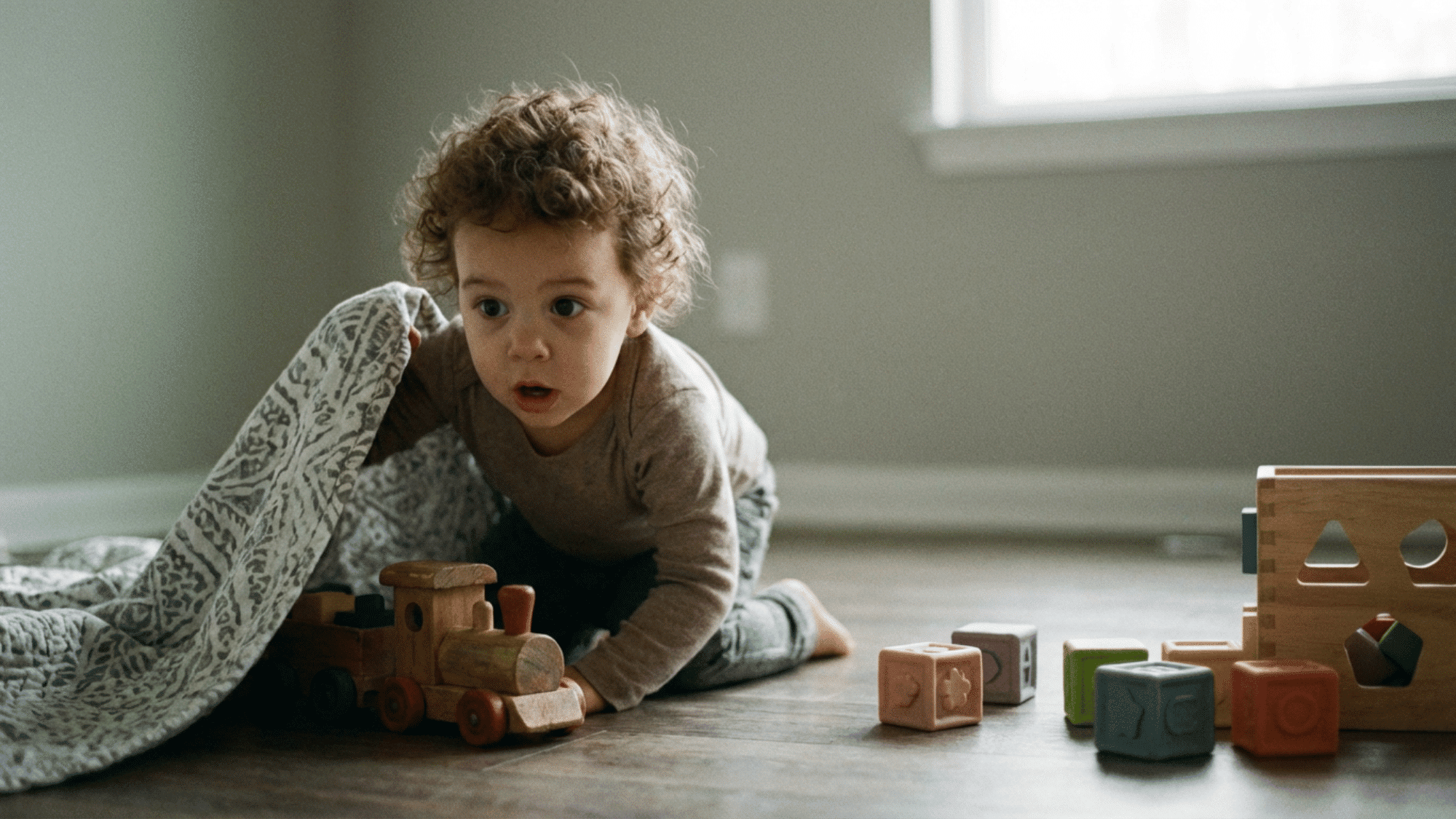 Toddler finding hidden toy showing curiosity and problem solving skills
