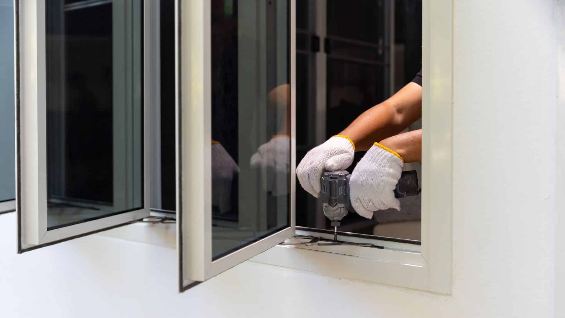 Worker using a power drill to replace a window frame, installing a new window unit into an existing opening for a secure and energy-efficient fit