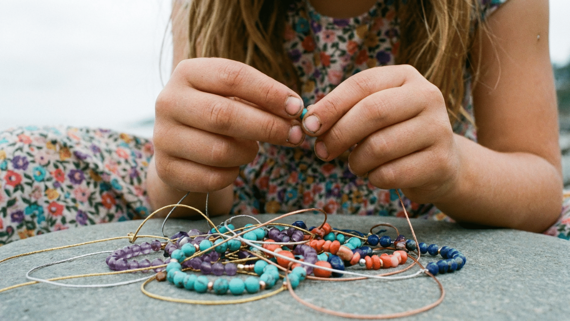 Young girl making DIY beaded bracelets with colorful beads