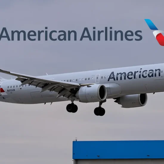 American Airlines plane landing against cloudy sky with hangar roof visible below