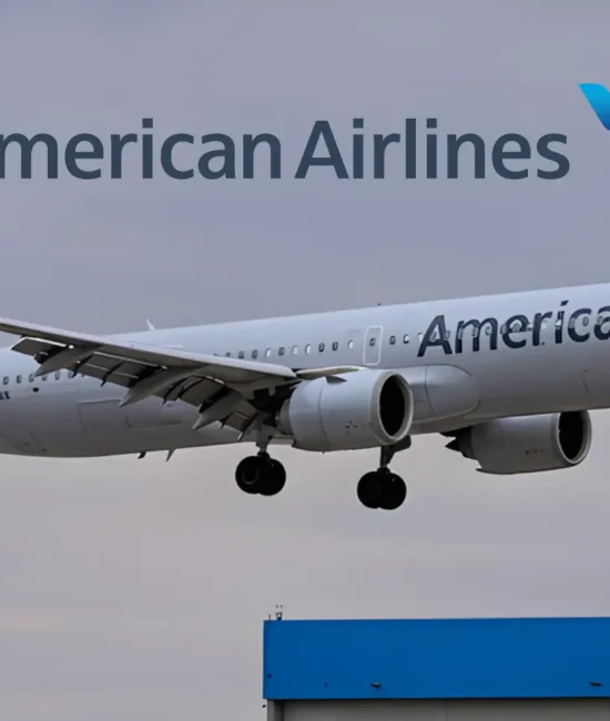 American Airlines plane landing against cloudy sky with hangar roof visible below