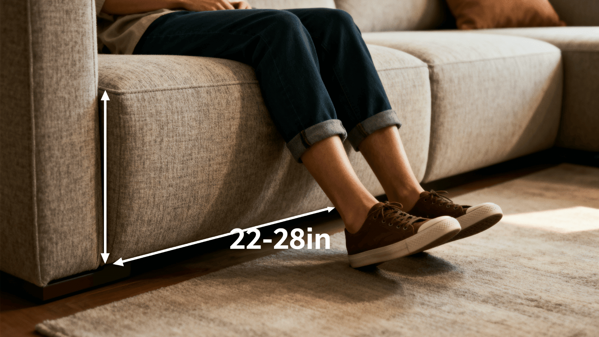 Close-up of sofa seat depth (22–28 inches) with person seated, showing leg comfort and support in a warm, modern living room