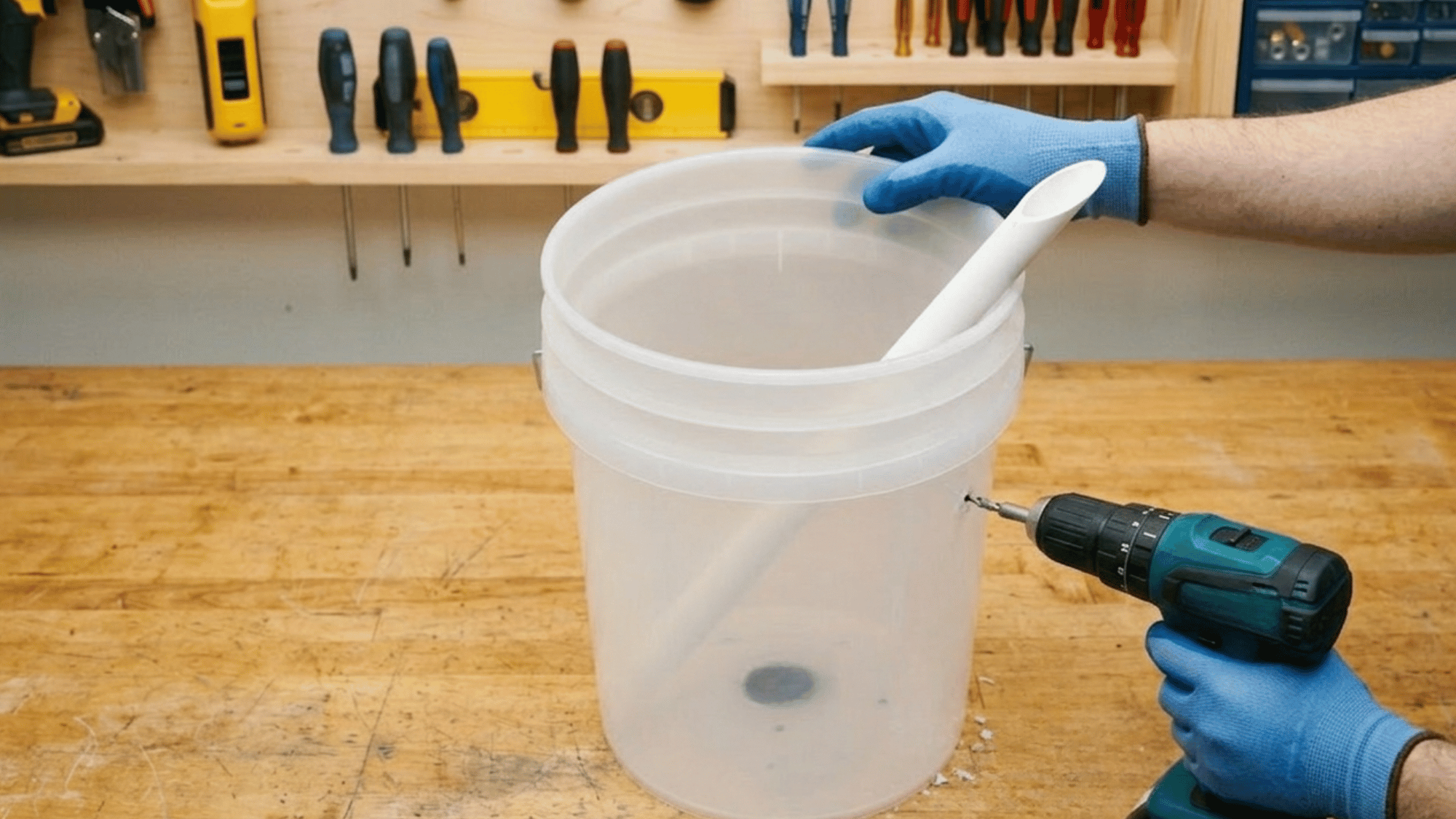 Drilling drainage and overflow holes in buckets for DIY self watering planter system.