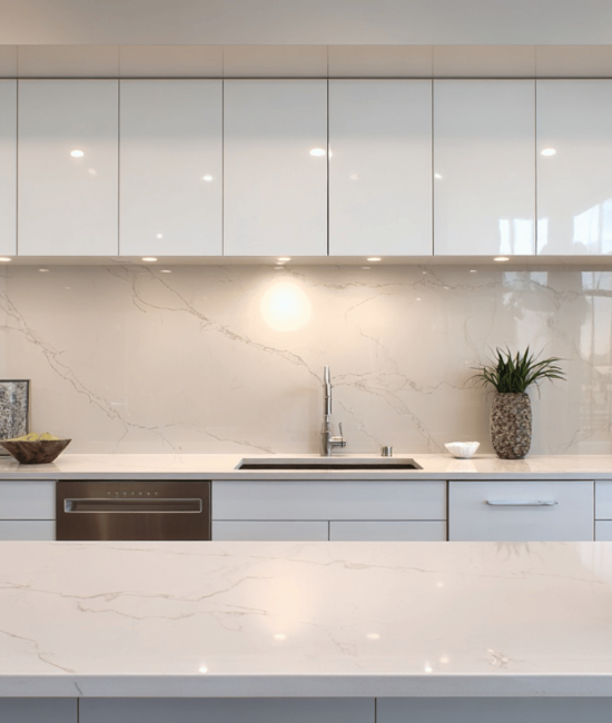 Modern white kitchen featuring glossy handleless cabinetry, a marble-look quartz backsplash and island countertop.