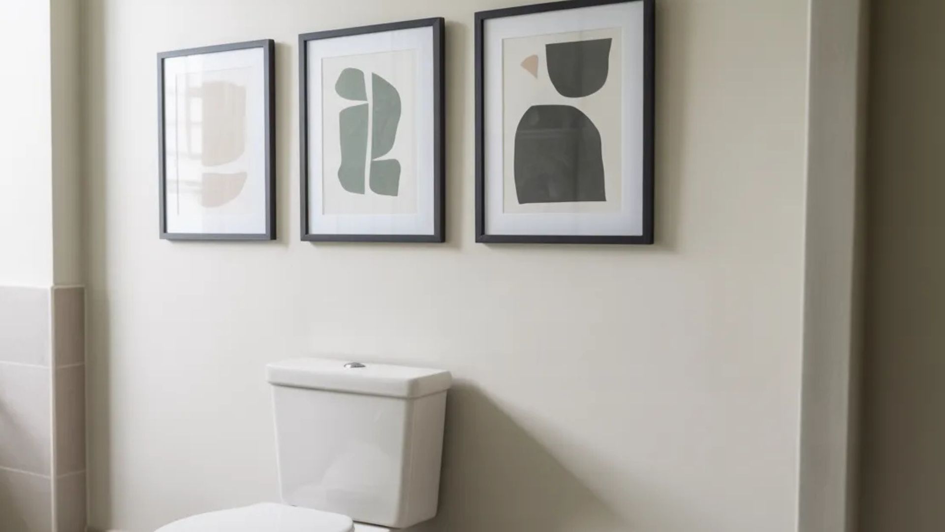 bathroom wall decorated with framed art prints arranged above toilet adding personality visual interest and balance to the space