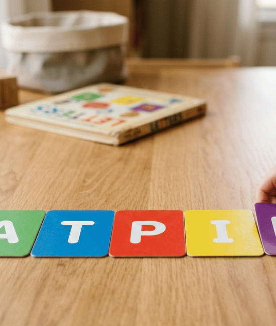 Child learning letters in SATPIN order with simple flashcards on a clean table.