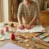 child's paint-stained hands crafting a handmade mother's day card on a sunny wooden table