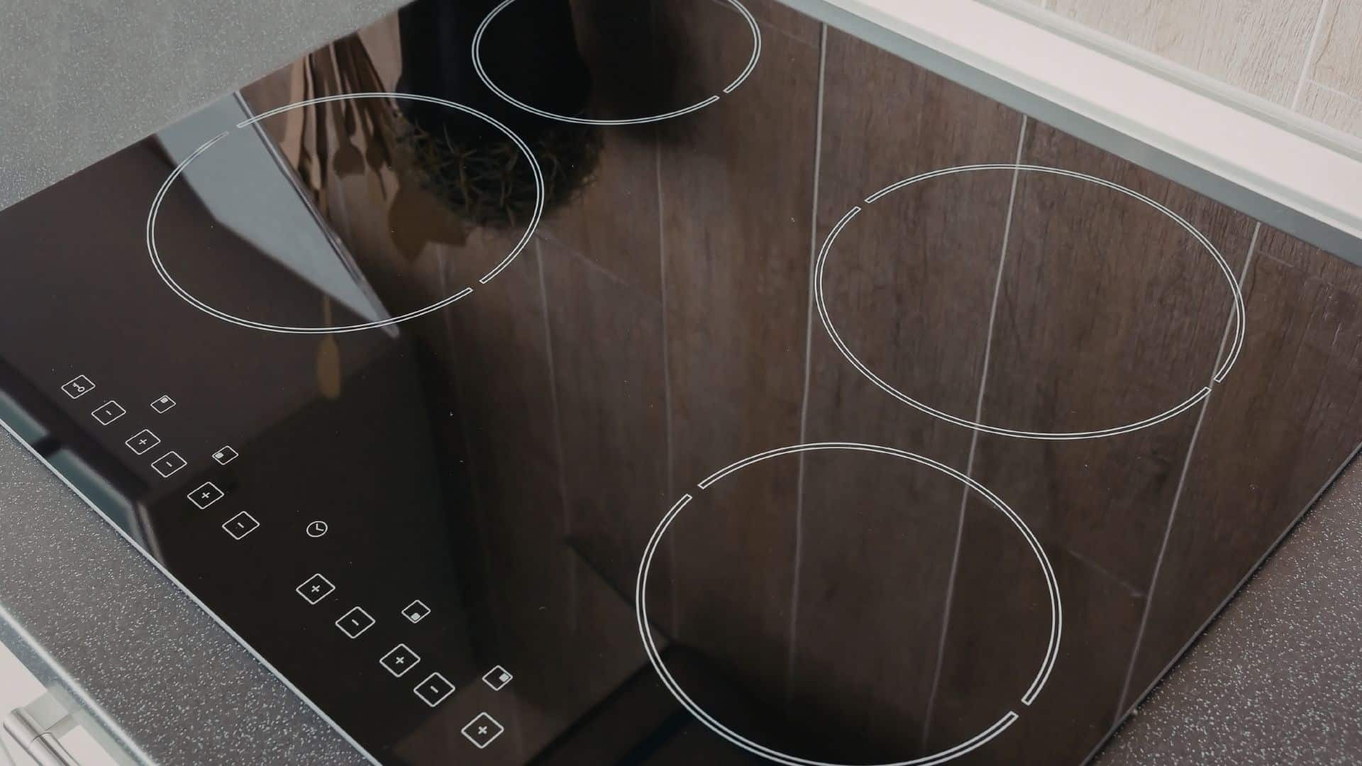 Clean black glass cooktop with smooth burners and touch controls, ideal example for how to clean stove burners on glass top surfaces safely