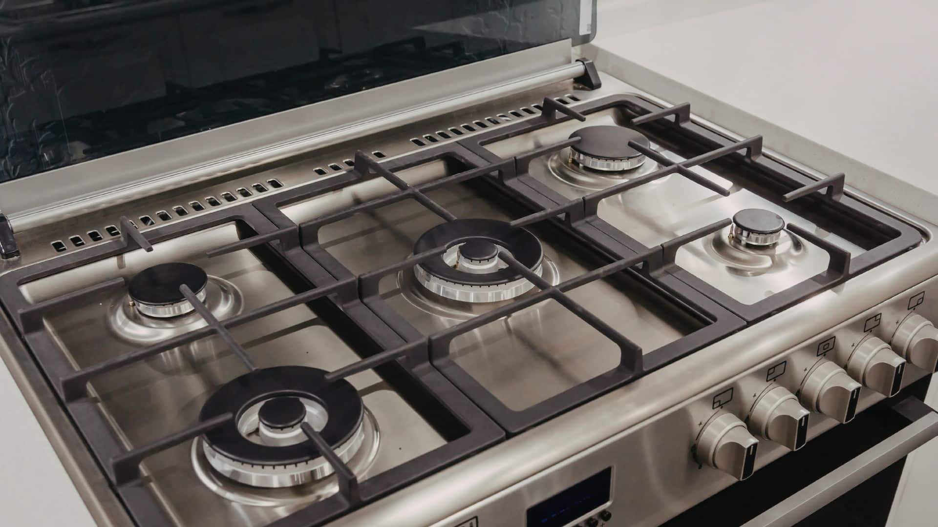Clean stainless steel gas stove with multiple burners and grates, showing setup before learning how to clean stove burners effectively