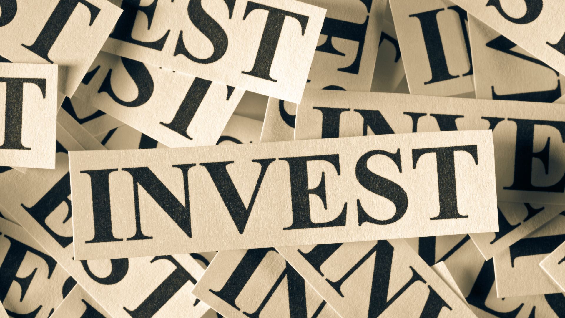 Close-up of paper cutouts spelling “invest,” symbolizing the benefits of investing, wealth growth, financial planning, and long-term money management strategy