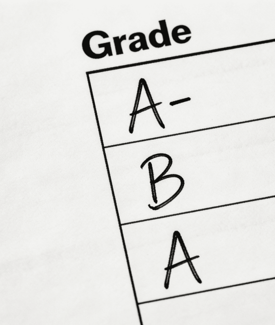 Close-up of report card showing handwritten grades like A and B under grade column.