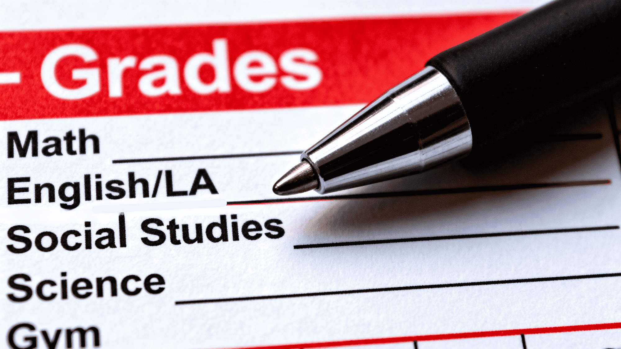 Close-up of report card with grades section and pen pointing at English subject line