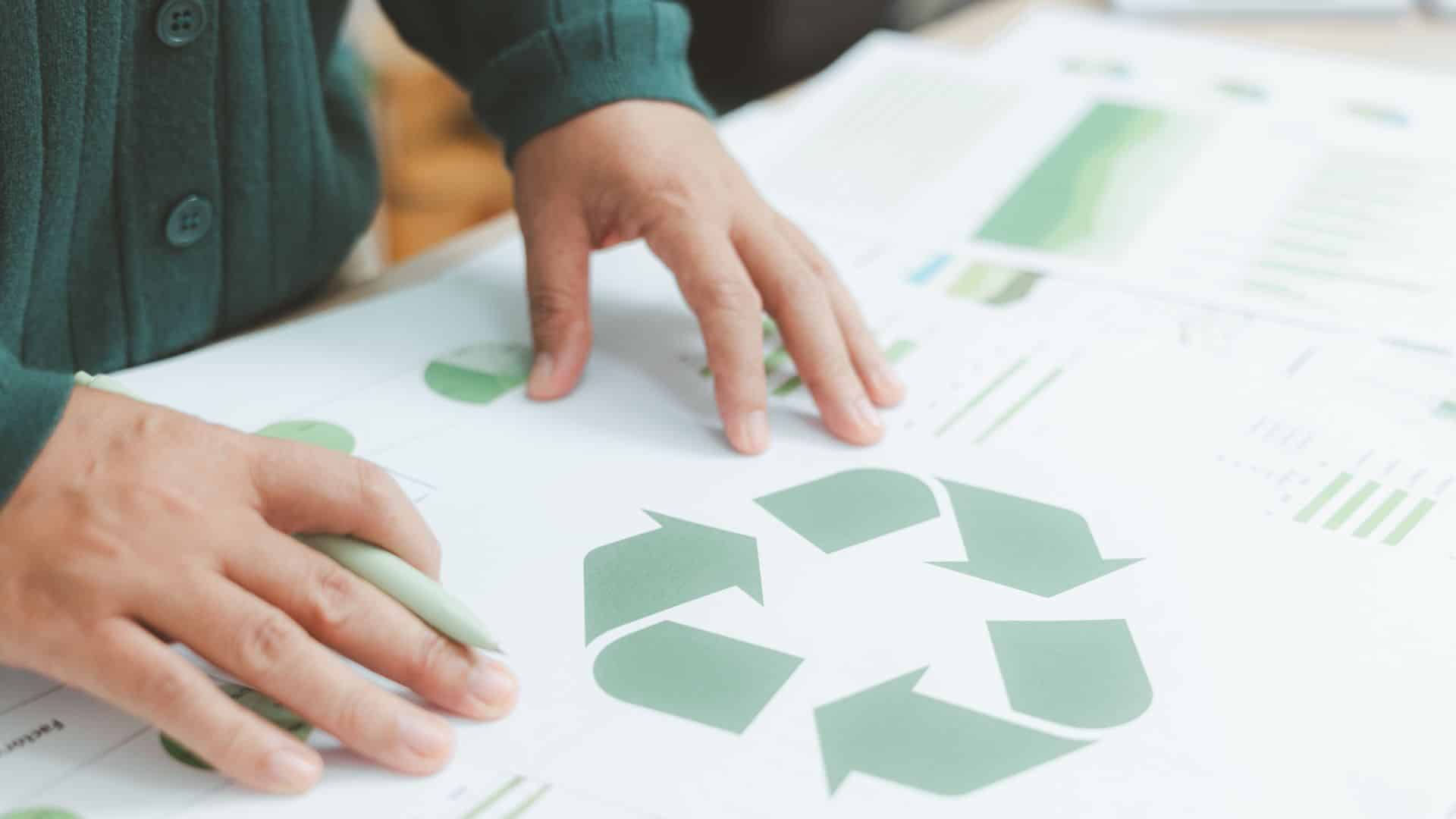 _Energy efficiency upgrades planning with hands reviewing sustainability charts and recycling symbol, highlighting eco-friendly home improvement strategies