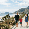 Family enjoying scenic US vacation with beach mountains and city skyline in background