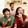 Group of kids laughing, pointing, and playing a fun game together on a couch in a bright, cozy living room setting