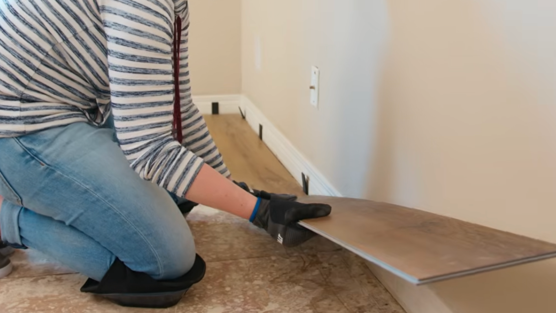 Installing first row of vinyl plank flooring with spacers to maintain proper expansion gap