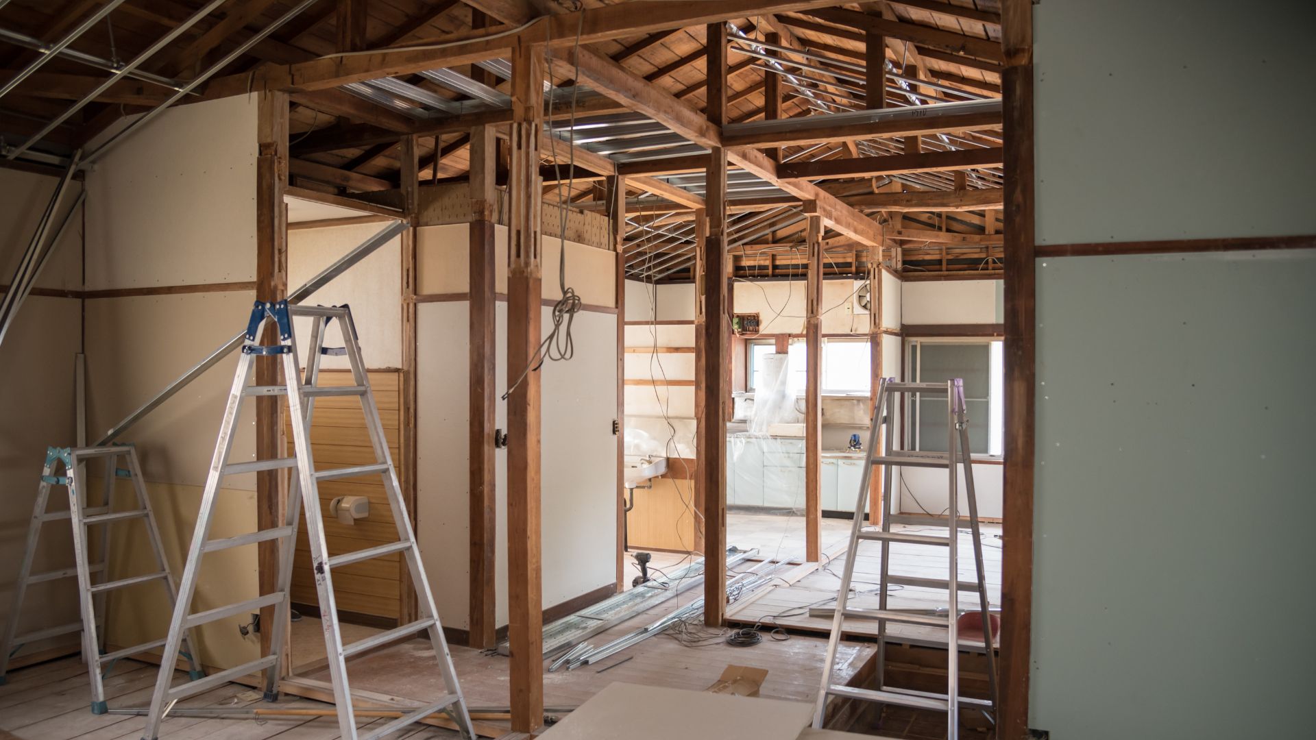 Interior home renovation in progress with exposed wooden framing, ladders, and wiring, showing practical renovation tips for planning layout and structure
