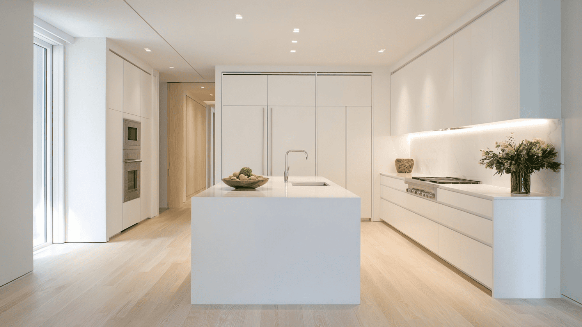 Minimalist white floor-to-ceiling kitchen cabinets in a bright modern kitchen