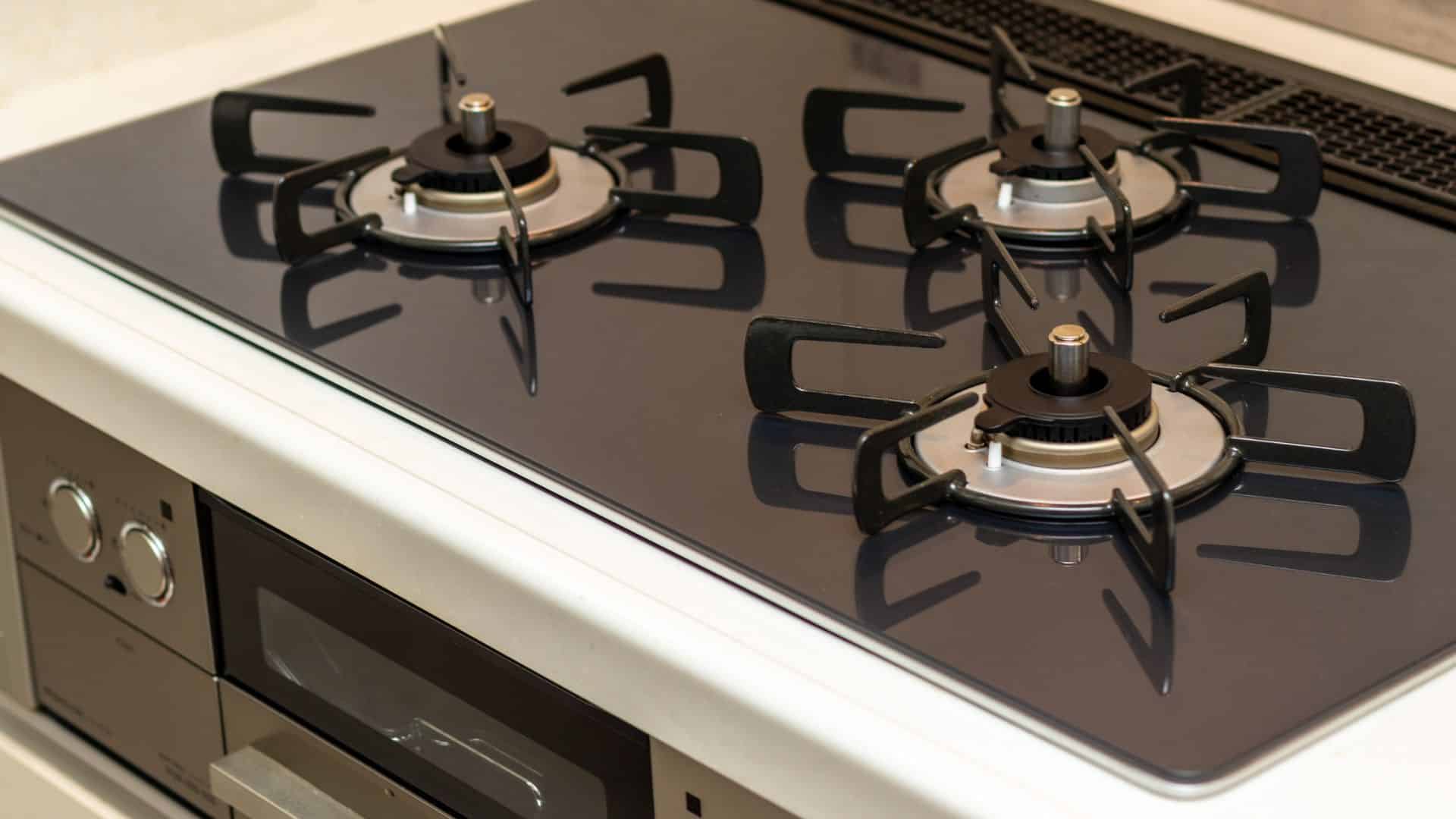 Modern gas stove with clean black glass surface and three burners, showing proper setup for how to clean coil stove burners safely and effectively