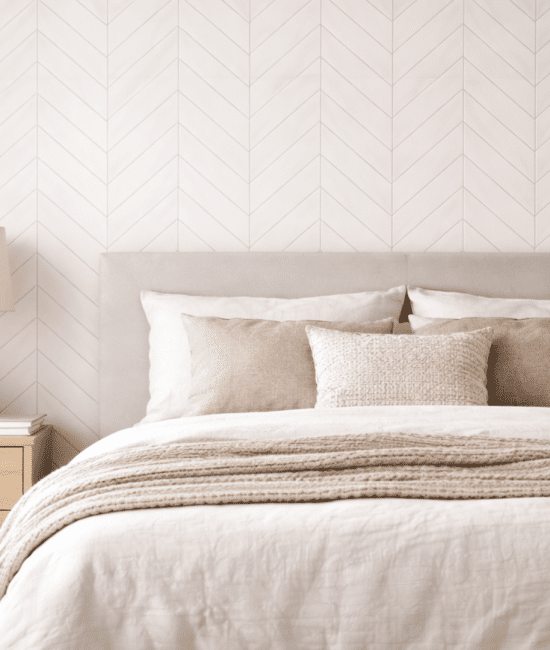 Neutral bedroom with soft herringbone wall pattern, minimal decor, light wood furniture, and cozy textured bedding in warm natural light