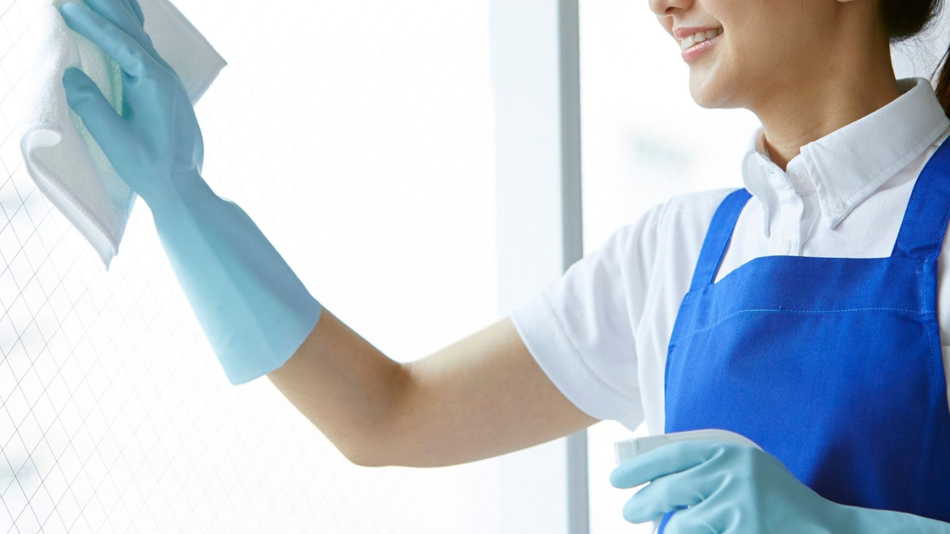 Person cleaning a window with cloth and spray, demonstrating streak-free results using a DIY glass cleaner solution at home