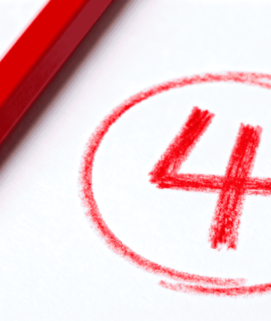 Red pencil beside circled number 4 on white paper representing a grading mark or top score